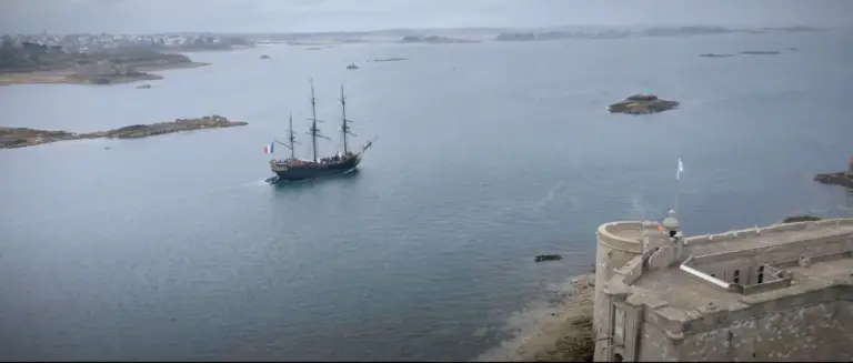 Le voilier L’Étoile du Roy navigue devant le Château du Taureau en baie de Morlaix, image captée depuis les airs.